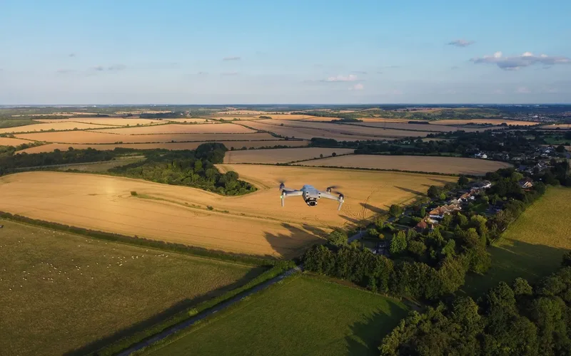 Drone comercial em voo de longo alcance sobre área rural, ilustrando operações BVLOS