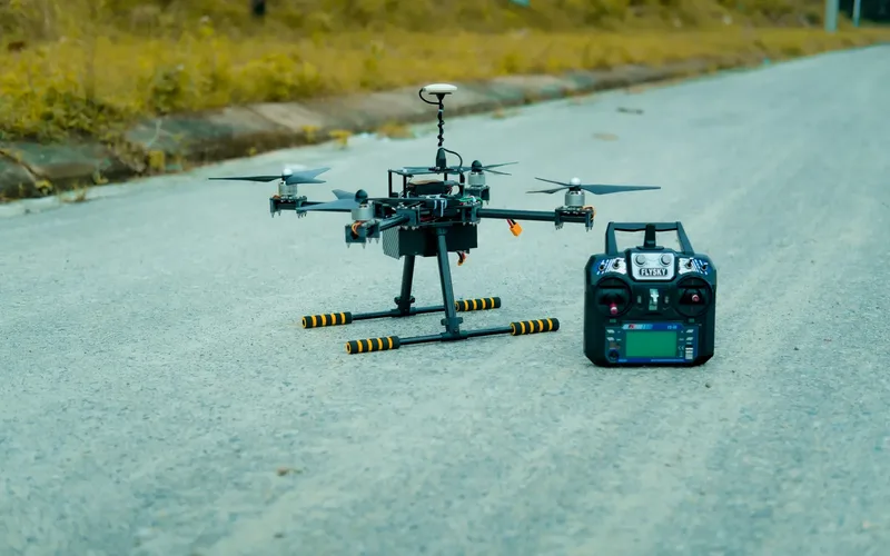 A large heavy-lift cargo drone hovering with an underslung payload on an airfield apron