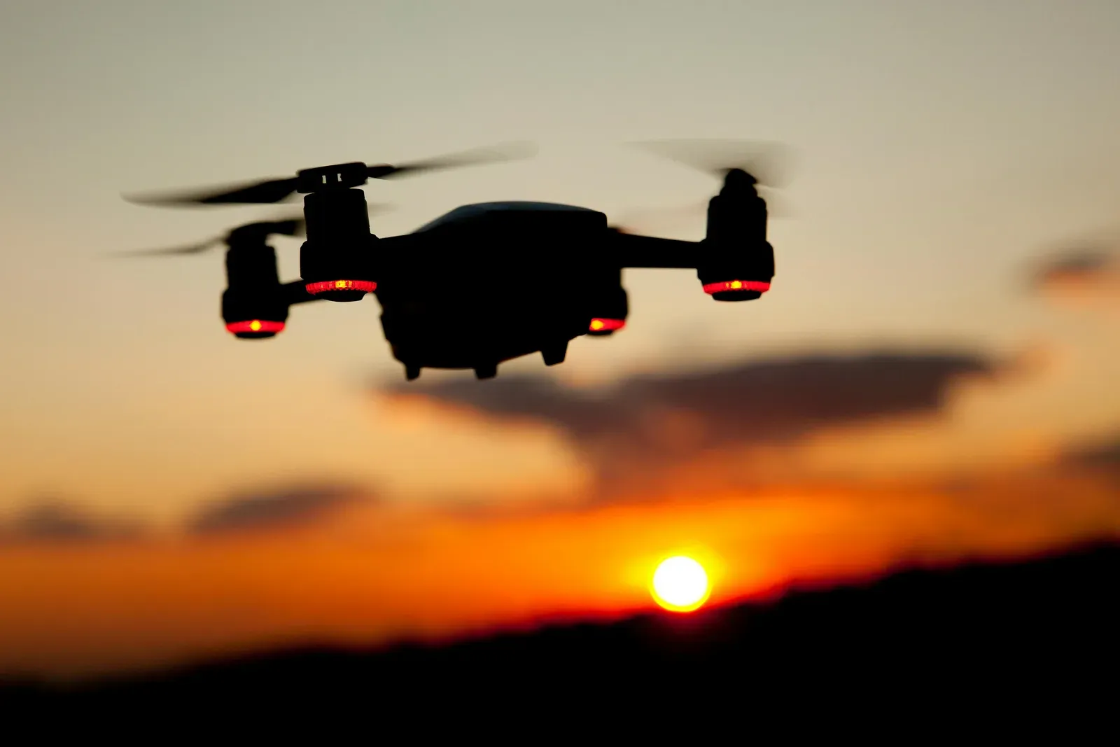Drone voando ao nascer do sol com luz dourada ao fundo