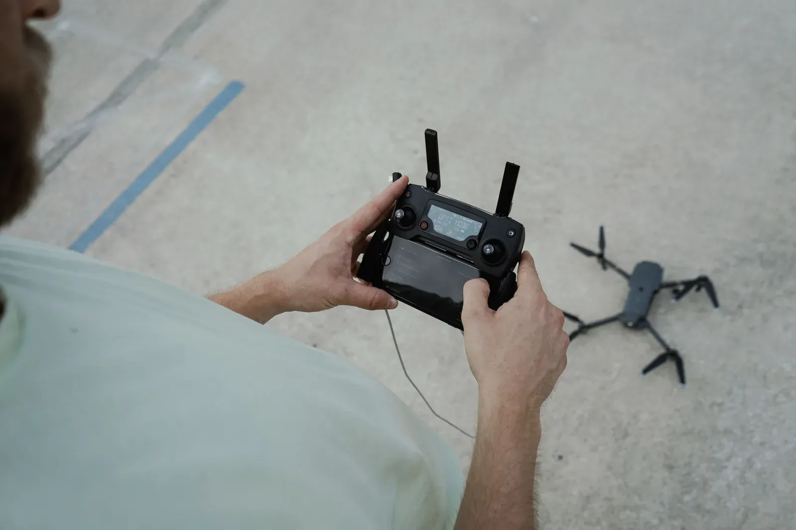 Piloto operando drone em linha de visada visual direta em campo aberto