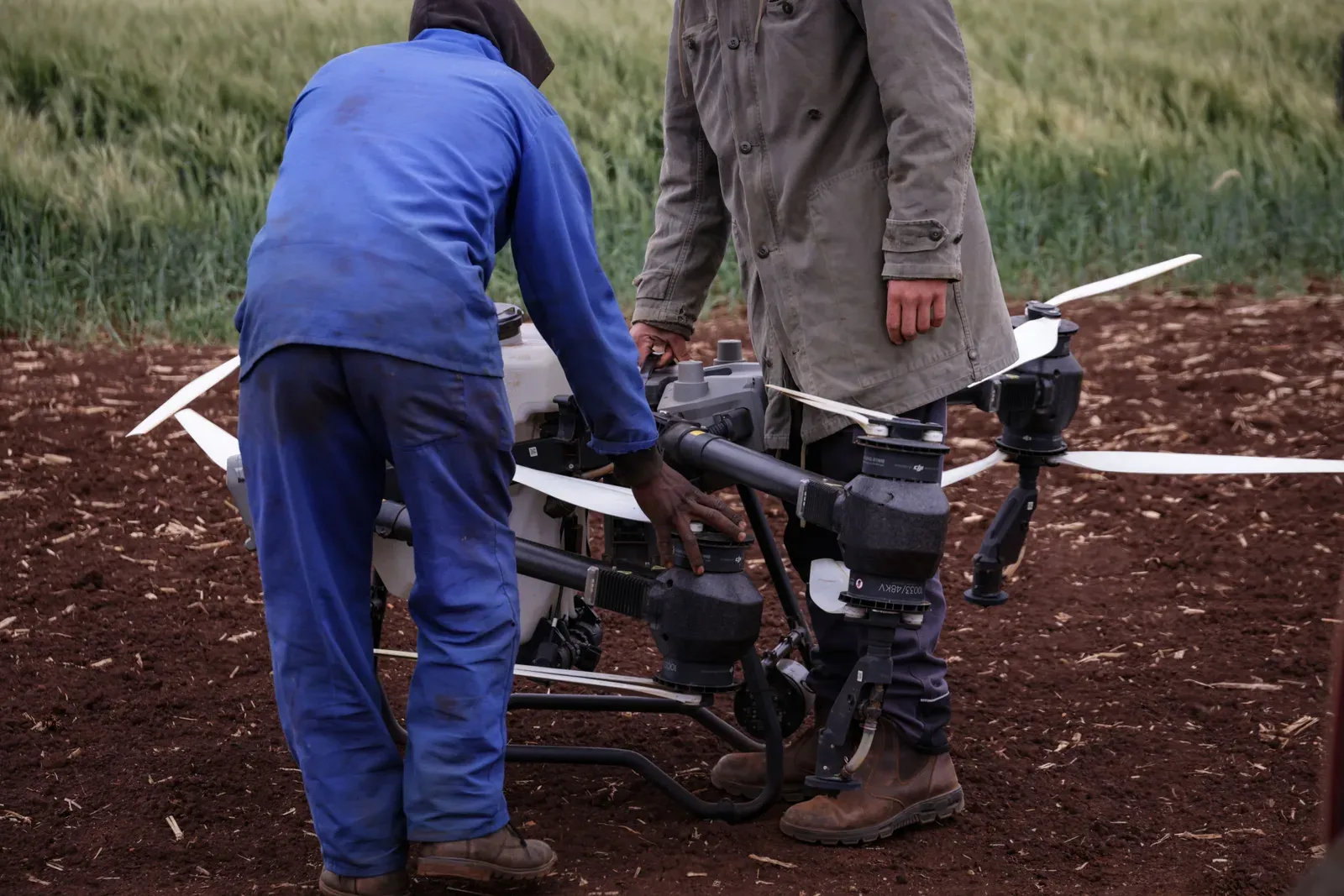 Operador realizando troca de baterias de drone agrícola em ponto de abastecimento no campo