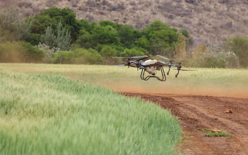 Large agricultural spray drone releasing mist over a green crop field