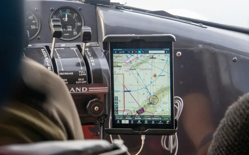 Operador de drone planejando voo em laptop com mapa aeronáutico ao lado de um quadricóptero