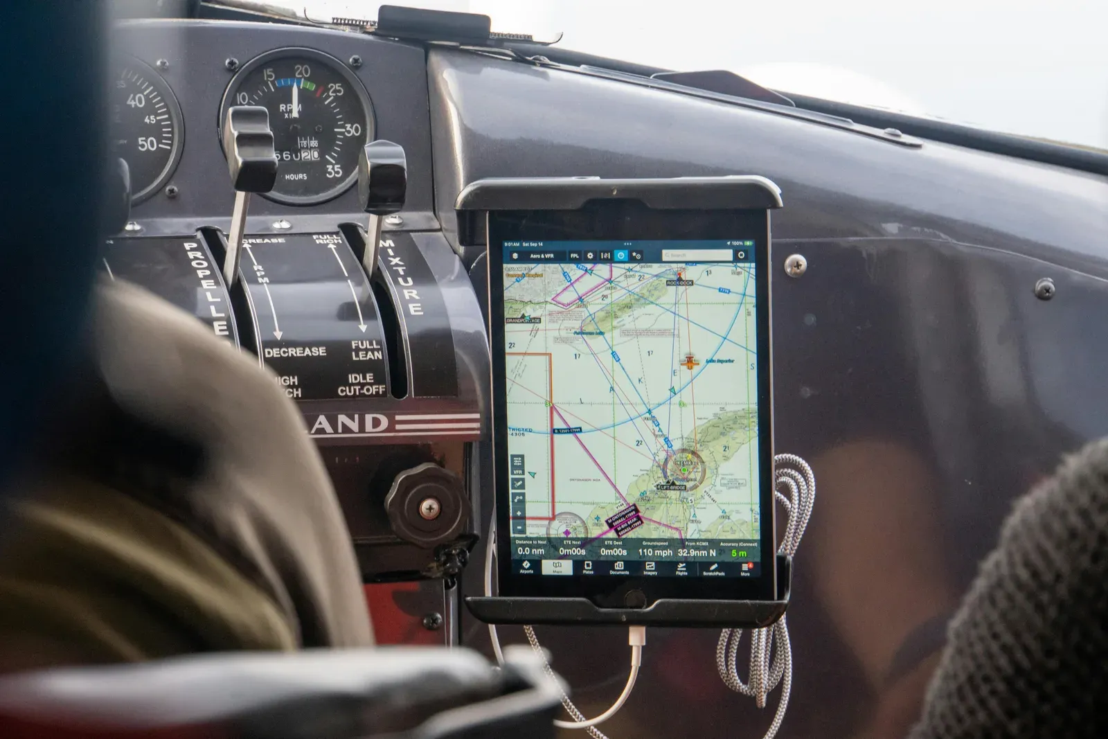 Operador de drone planejando voo em laptop com mapa aeronáutico ao lado de um quadricóptero