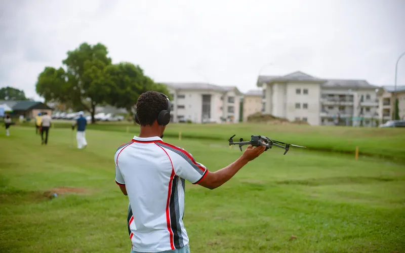 Drone de entrega sobrevoando bairro residencial com pacote suspenso