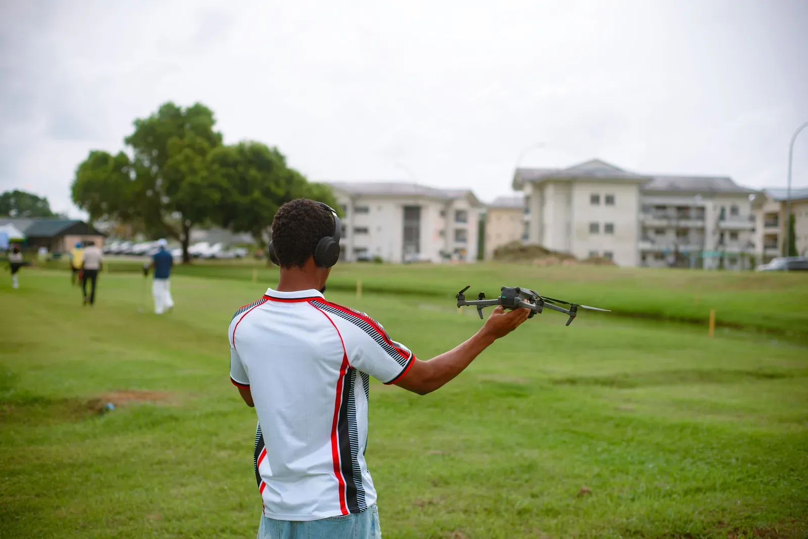 Drone de entrega sobrevoando bairro residencial com pacote suspenso