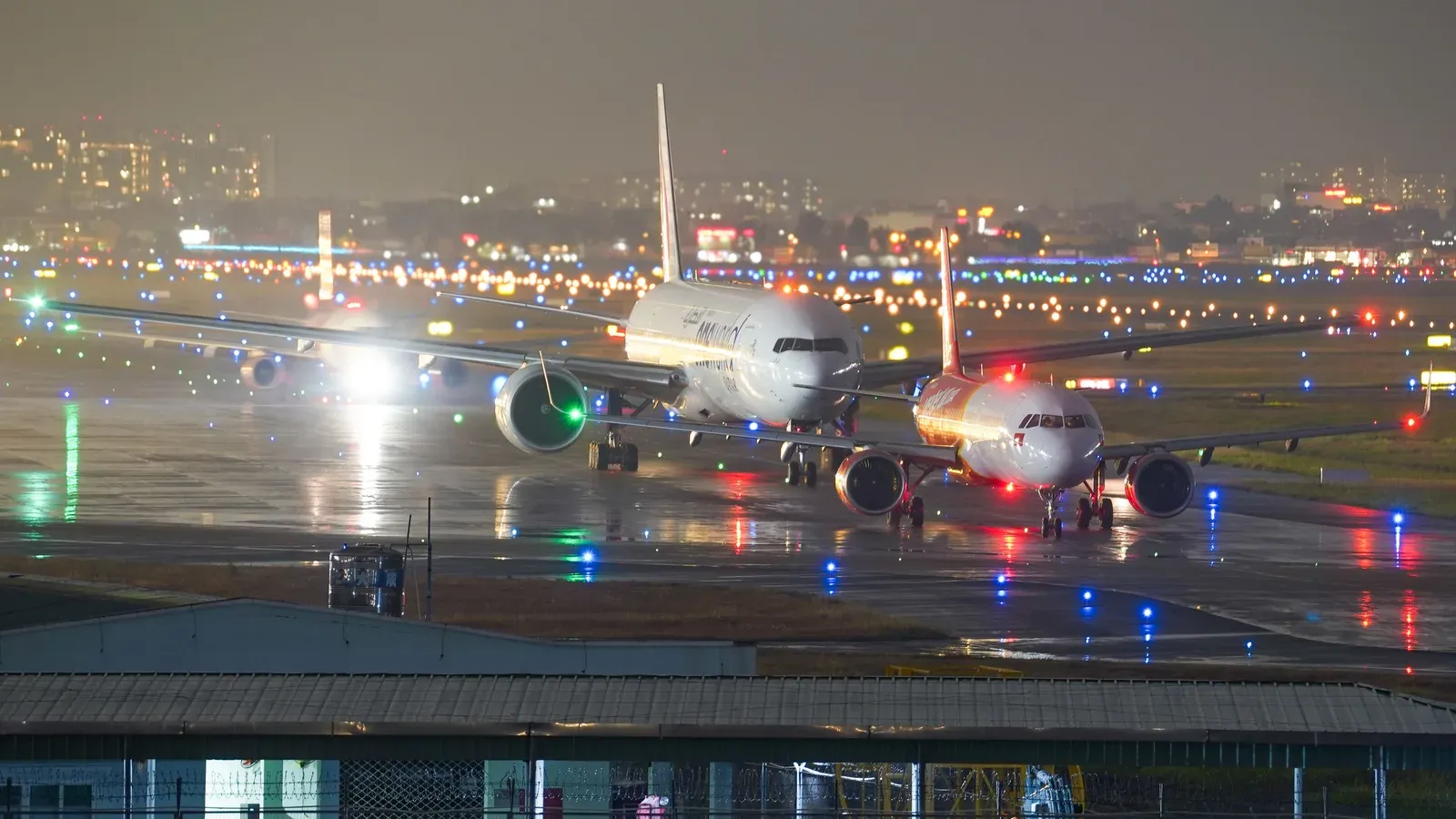 Torre de controle de aeroporto iluminada à noite com pista deserta ao fundo