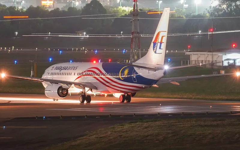 Torre de controle de aeroporto iluminada durante a noite com pista ao fundo
