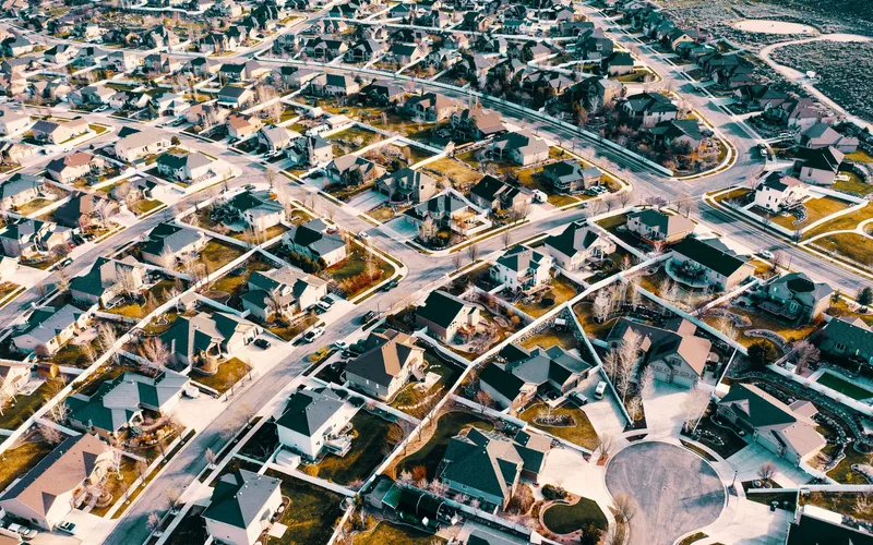 Fixed-wing delivery drone flying above a suburban neighborhood