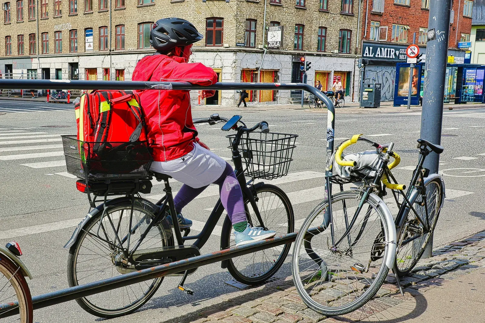 Entregador de bicicleta com mochila térmica em rua urbana
