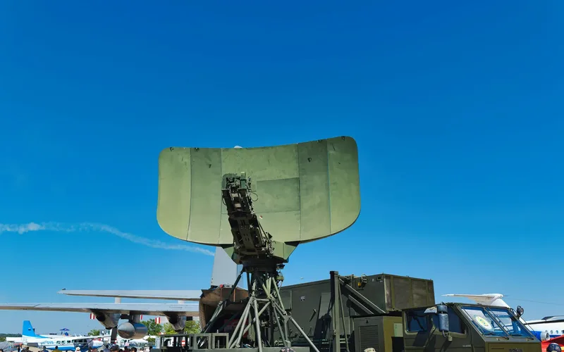 Sistema militar antiaéreo com radar apontado para o céu e operadores em campo