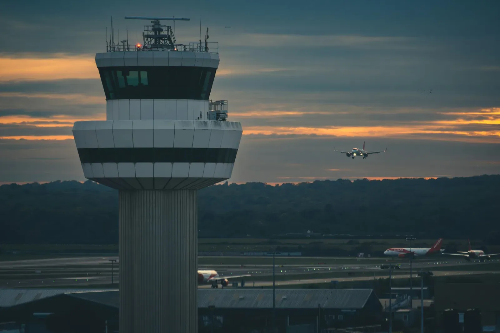Torre de controle de aeroporto comercial movimentado ao entardecer