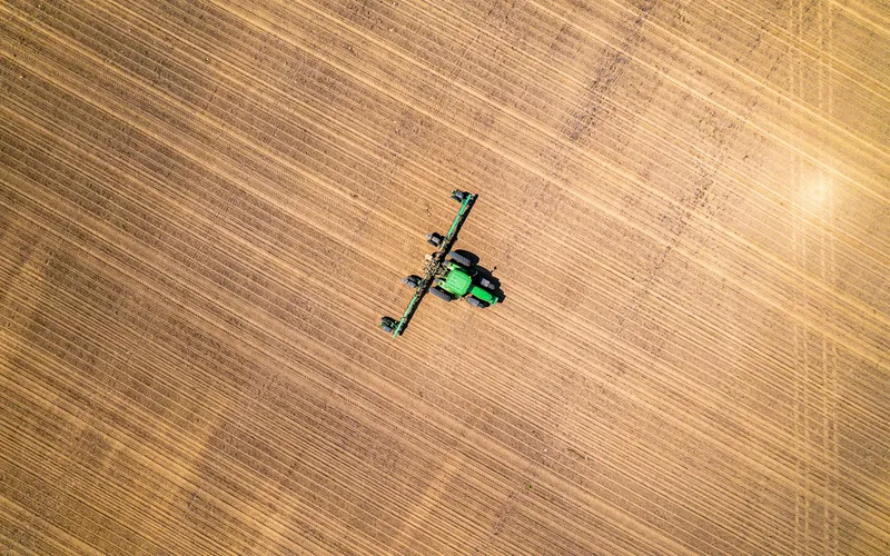 Drone agrícola de grande porte pulverizando lavoura verde ao amanhecer